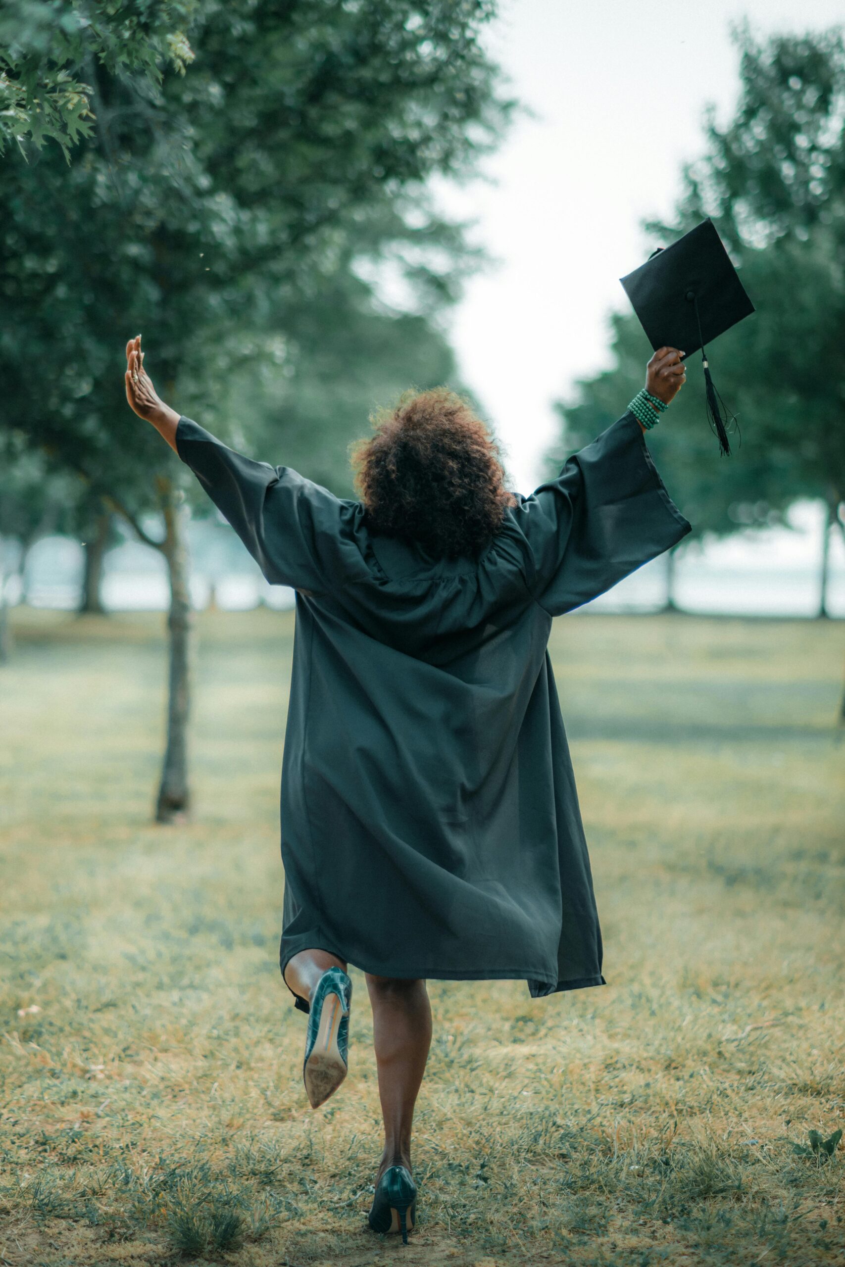 Services A jubilant graduate celebrating in a park, holding an academic cap, symbolizing success.